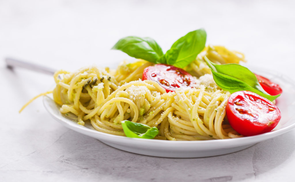 Homemade spaghetti pasta with avocado, tomato and basil sauce, closeup